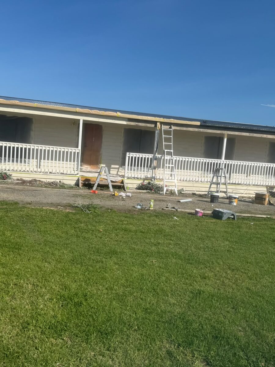 Home being repainted with drop sheets and equipment on the lawn